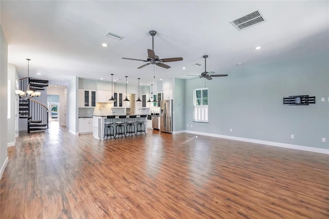 living room featuring dark wood-type flooring and ceiling fan with notable chandelier