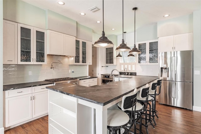 kitchen with a kitchen island with sink, dark hardwood / wood-style floors, stainless steel appliances, hanging light fixtures, and white cabinetry