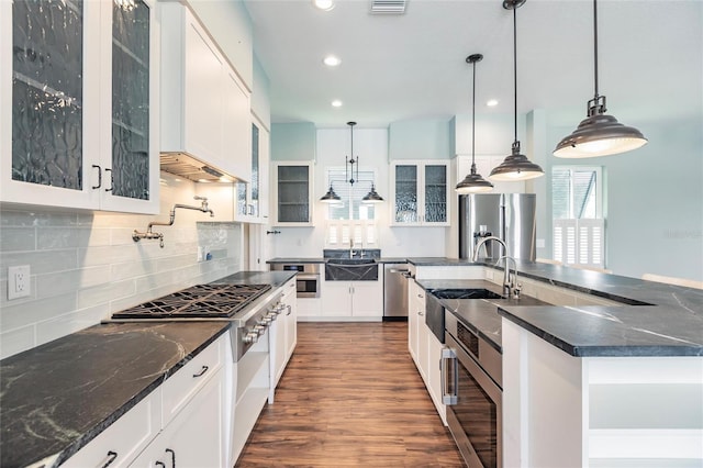 kitchen with dark hardwood / wood-style floors, a large island with sink, stainless steel appliances, hanging light fixtures, and white cabinets