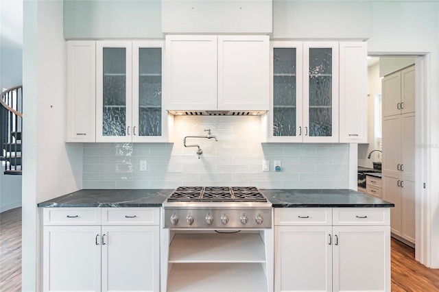 kitchen with tasteful backsplash, dark stone countertops, white cabinets, and light wood-type flooring