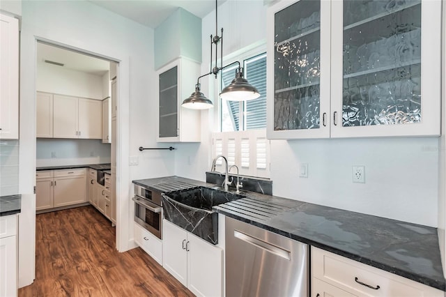 kitchen with stainless steel appliances, dark wood finished floors, glass insert cabinets, white cabinetry, and a sink
