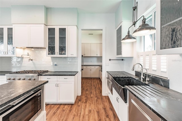 kitchen with white cabinets, hanging light fixtures, sink, wood-type flooring, and stainless steel appliances