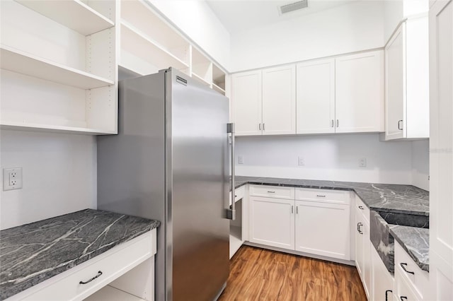 kitchen with white cabinets, visible vents, open shelves, light wood-style floors, and freestanding refrigerator