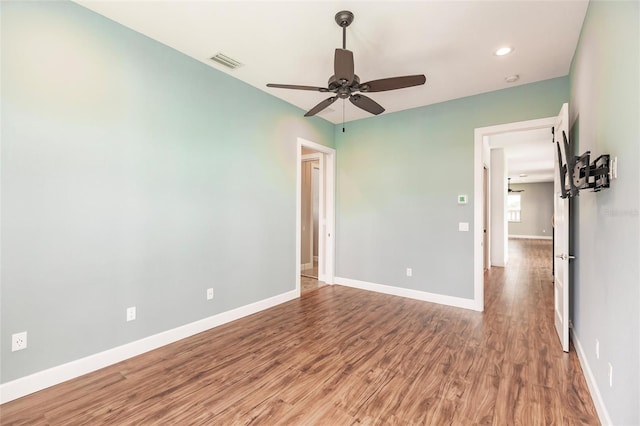 unfurnished room featuring baseboards, visible vents, a ceiling fan, and wood finished floors