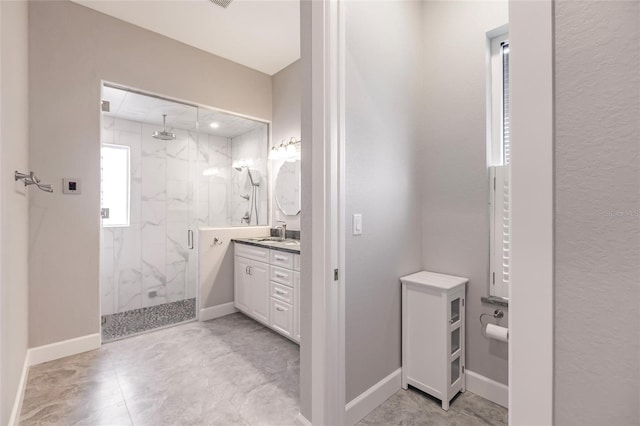 full bathroom featuring baseboards, vanity, and a marble finish shower