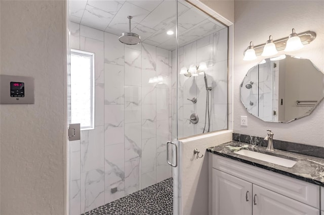bathroom featuring a textured wall, a stall shower, and vanity