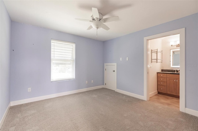 unfurnished bedroom with light carpet, ensuite bath, sink, and ceiling fan