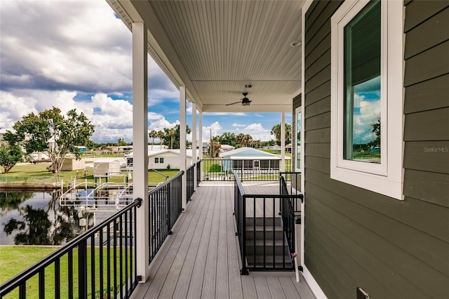 wooden deck featuring a water view, ceiling fan, and a yard