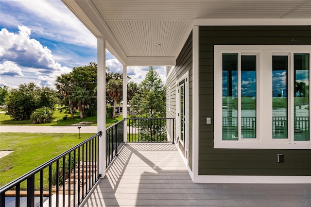 wooden terrace featuring a porch and a yard