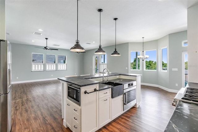 kitchen with dark hardwood / wood-style floors, sink, stainless steel appliances, hanging light fixtures, and white cabinets