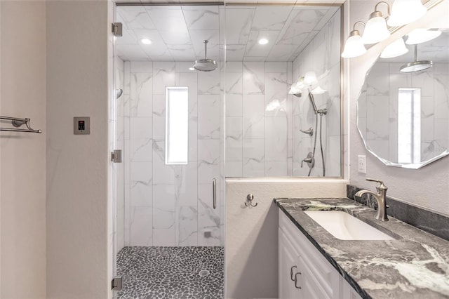 bathroom featuring a shower with door and vanity