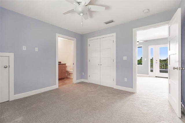 unfurnished bedroom featuring ceiling fan, a closet, light carpet, access to exterior, and ensuite bathroom