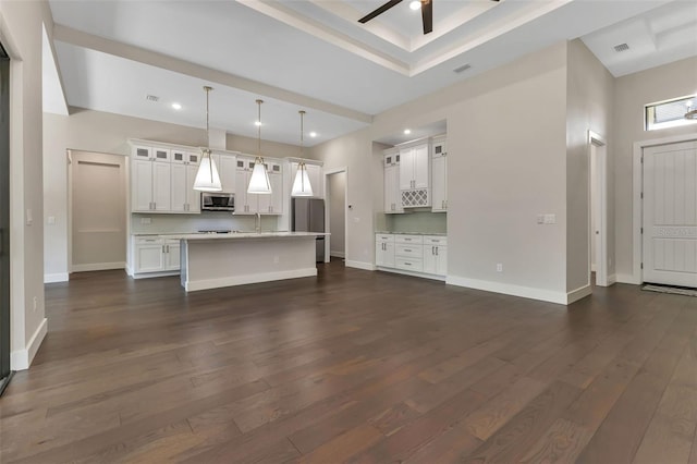 unfurnished living room with ceiling fan, dark hardwood / wood-style flooring, and a high ceiling