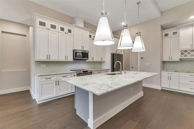 kitchen featuring decorative light fixtures, a center island with sink, decorative backsplash, stainless steel appliances, and white cabinets