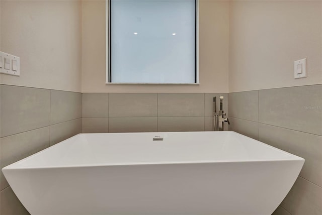 full bath with a soaking tub and tile walls