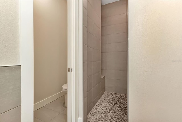 bathroom with tile patterned flooring, baseboards, a shower stall, and toilet