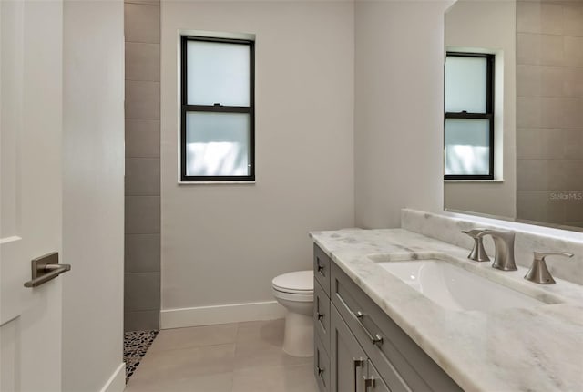 bathroom with toilet, a wealth of natural light, tile patterned flooring, and vanity