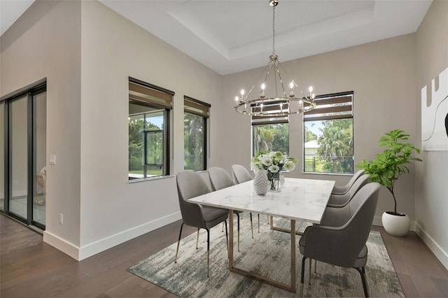 dining room featuring a raised ceiling, dark hardwood / wood-style floors, and a notable chandelier