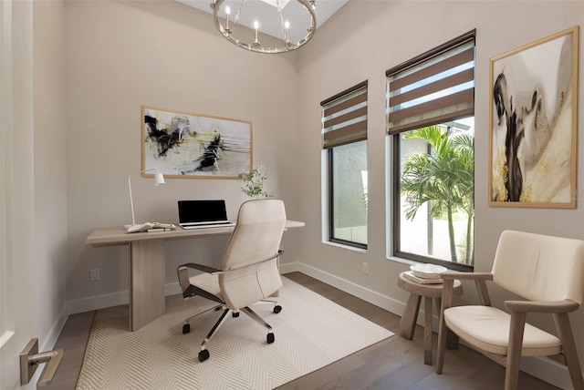 office with plenty of natural light, wood-type flooring, and a chandelier