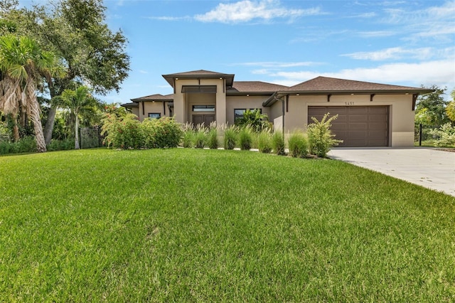 prairie-style house with a garage, concrete driveway, a front lawn, and stucco siding