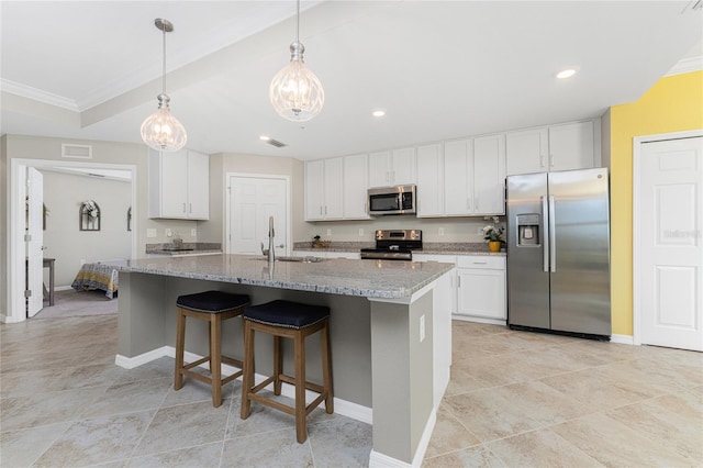 kitchen featuring light stone countertops, white cabinetry, appliances with stainless steel finishes, and a kitchen island with sink