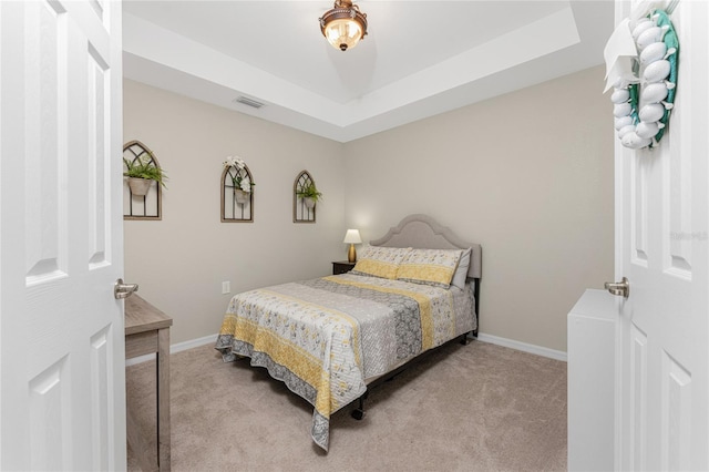 bedroom featuring light carpet and a raised ceiling