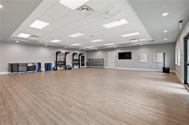 workout area featuring ceiling fan, a drop ceiling, and light hardwood / wood-style floors