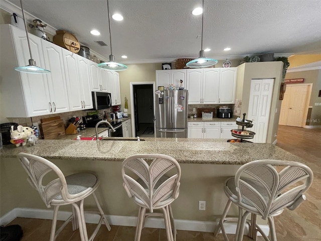 kitchen featuring a kitchen breakfast bar, hanging light fixtures, white cabinets, kitchen peninsula, and stainless steel appliances