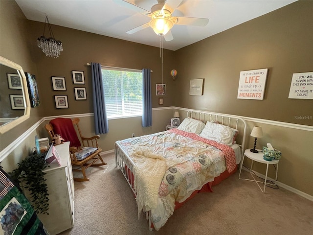 carpeted bedroom featuring ceiling fan with notable chandelier