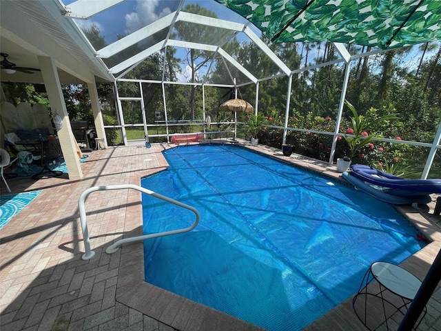 view of pool featuring ceiling fan, glass enclosure, and a patio