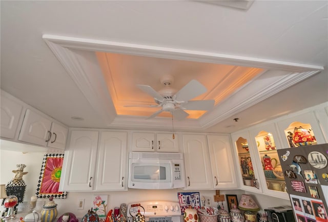 interior space featuring white cabinets, stainless steel refrigerator, a raised ceiling, crown molding, and ceiling fan