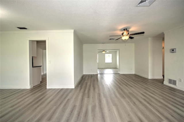 empty room with a textured ceiling, crown molding, ceiling fan, and light hardwood / wood-style flooring