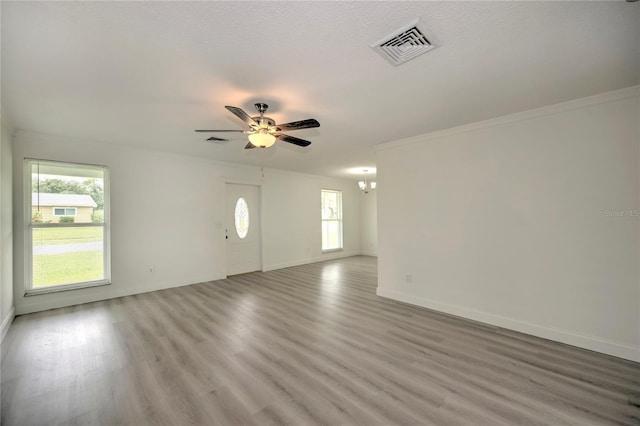 1638 Harmony Dr, Port Charlotte, FL 33952 - unfurnished living room with ceiling fan with notable chandelier, wood finished floors, crown molding, and visible vents
