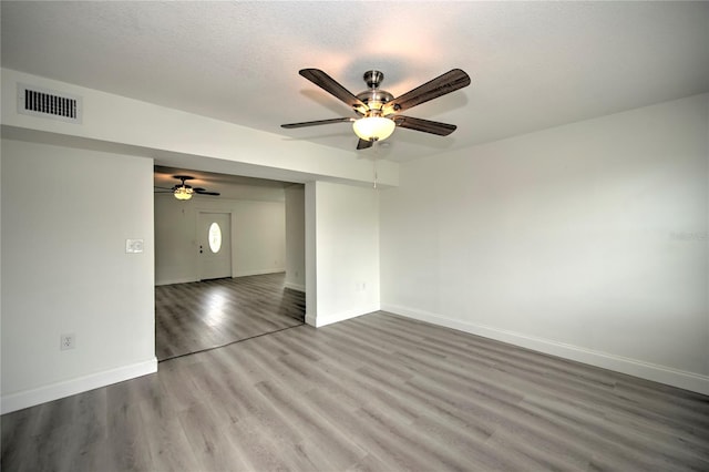 empty room with a textured ceiling, ceiling fan, and hardwood / wood-style flooring