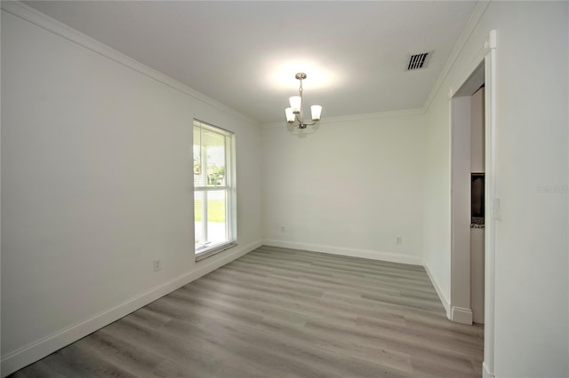 unfurnished room featuring ornamental molding, an inviting chandelier, and light hardwood / wood-style floors