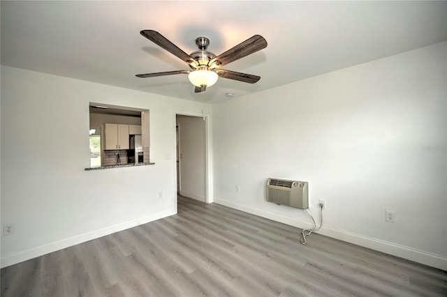 spare room featuring ceiling fan, light hardwood / wood-style floors, and a wall mounted AC