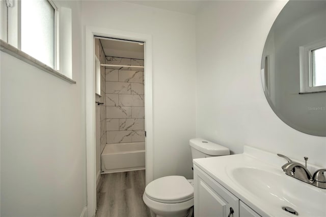 full bathroom featuring hardwood / wood-style floors, vanity, toilet, and tiled shower / bath combo