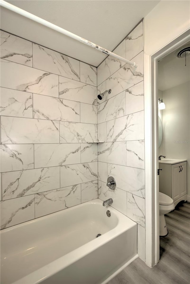 full bathroom featuring wood-type flooring, tiled shower / bath, vanity, and toilet