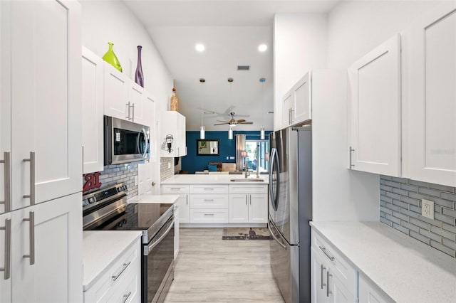 kitchen with white cabinetry, light hardwood / wood-style flooring, backsplash, appliances with stainless steel finishes, and ceiling fan