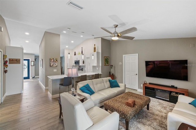 living room featuring lofted ceiling, ceiling fan, and light hardwood / wood-style floors