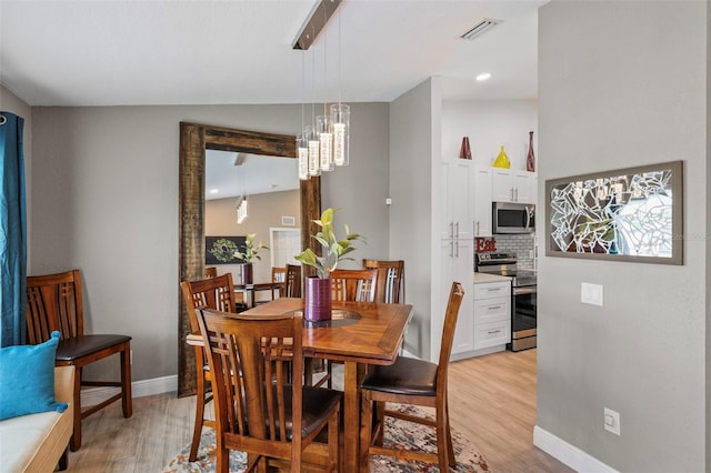 dining area featuring a notable chandelier, lofted ceiling, and light hardwood / wood-style floors