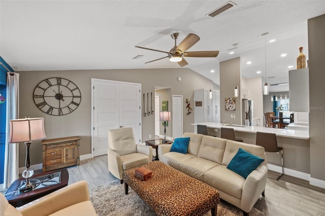 living room featuring lofted ceiling, sink, ceiling fan, and light hardwood / wood-style flooring