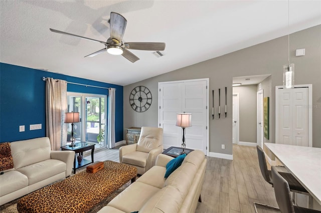 living room featuring light hardwood / wood-style flooring, vaulted ceiling, ceiling fan, and a textured ceiling