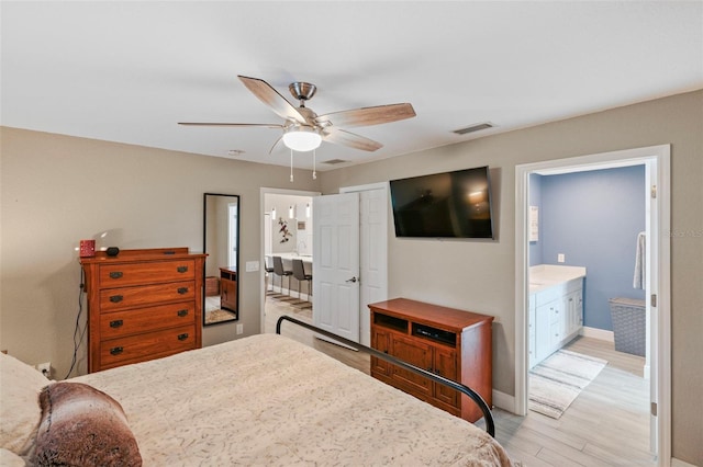 bedroom featuring light hardwood / wood-style floors, ensuite bath, ceiling fan, and a closet