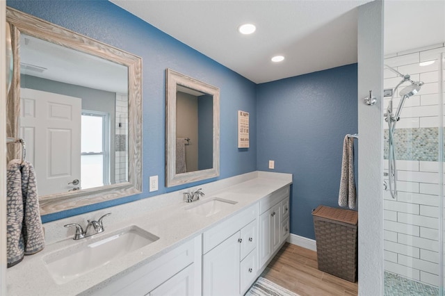 bathroom with a tile shower, vanity, and hardwood / wood-style flooring