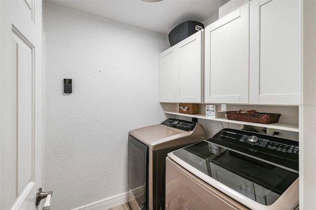 washroom with cabinets, washer and dryer, and hardwood / wood-style flooring