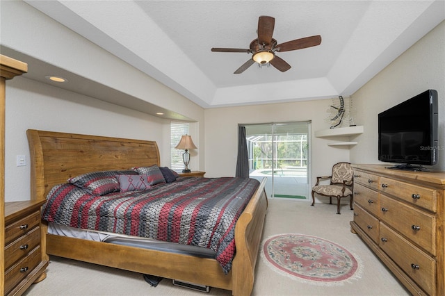 bedroom with a tray ceiling, access to exterior, light carpet, and ceiling fan