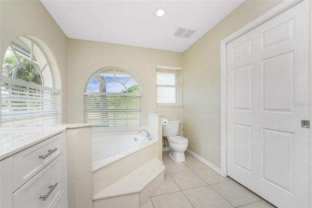 bathroom with tile patterned floors, toilet, a tub to relax in, and a wealth of natural light