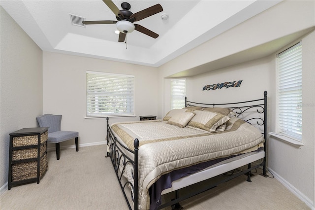 bedroom featuring light carpet, a raised ceiling, and ceiling fan