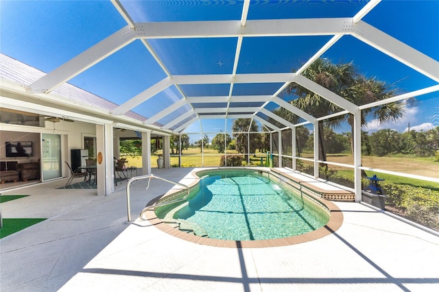 view of swimming pool featuring a patio, glass enclosure, and ceiling fan